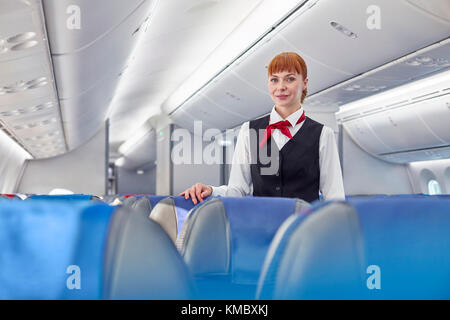 Portrait selbstbewusste weibliche Flugbegleiterin im Flugzeug Stockfoto
