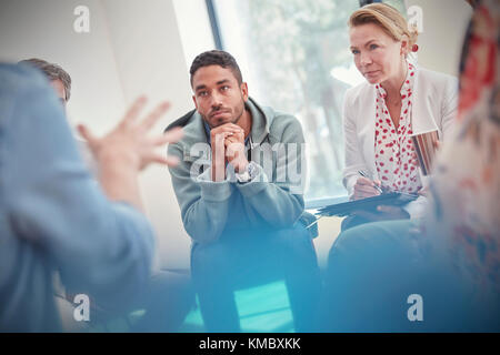 Aufmerksamer Mann und Frau, die in der Gruppentherapie zuhören Stockfoto