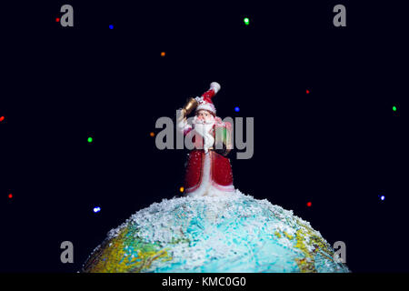 Weihnachtsmann stehend auf einer Weltkugel. Stockfoto