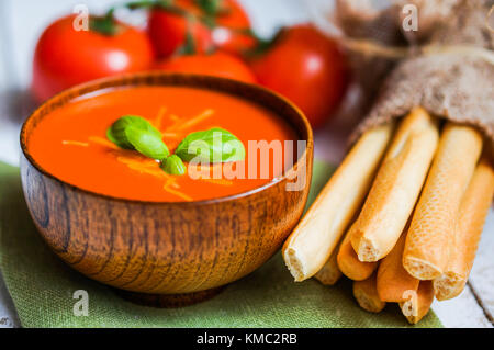 Tomaten Suppe mit Brot klebt und Basilikum auf hölzernen Hintergrund Stockfoto