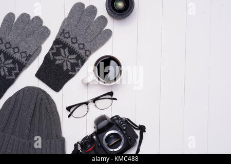 Winter Herren casual Outfits mit Kamera, Kaffeetasse und Brillen auf hölzernen Hintergrund Stockfoto