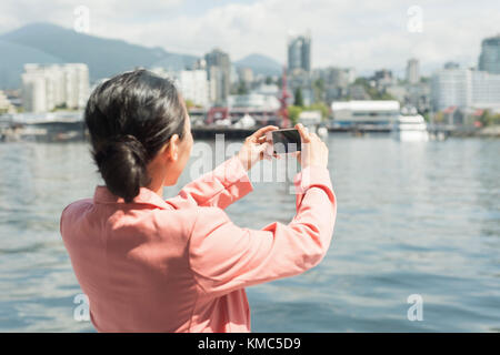 Asian Woman mit einem Foto von der Skyline der Fähre Stockfoto