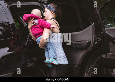 Mutter hält ihr Baby in der Nähe des Autos Stockfoto