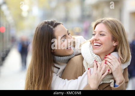 Zwei glückliche Freunde scherzend und lachend auf der Straße im Winter Stockfoto