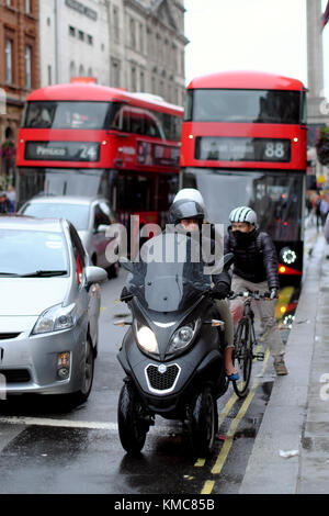 Dreirädrige Roller, Radfahrer, Autos und Busse auf der Straße, London, England, Großbritannien Stockfoto