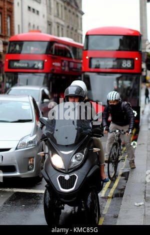 Dreirädrige Roller, Radfahrer, Autos und Busse auf der Straße, London, England, Großbritannien Stockfoto