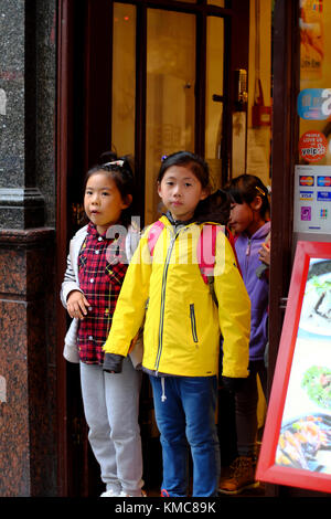 Chinesische Schule Kinder stehen im Eingang des Shop in Chinatown, Soho, London, England, Großbritannien Stockfoto