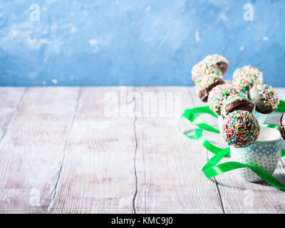 Nahaufnahme des bunten Schokoladenkuchen Pops mit Zucker Streusel in kleinen Tassen auf hölzernen Tisch. Kopieren Sie Platz Stockfoto