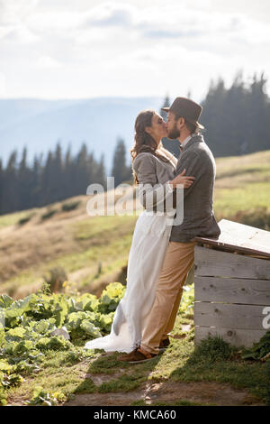 Brautpaar stand, umarmen und küssen während der Flitterwochen auf den Hintergrund der Karpaten. Stockfoto
