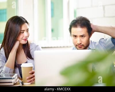 Zwei jungen asiatischen Kollegen Kollegen Mannschaftskameraden zusammen arbeiten im Büro Analyse Bericht mit Laptop. Stockfoto