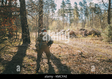 Nicht identifizierte re-Enactor als Soldat der Vereinigten Staaten von Amerika Infanterie des Zweiten Weltkriegs versteckte mit Sub gekleidet - Maschinengewehr im Wald bei histo Stockfoto