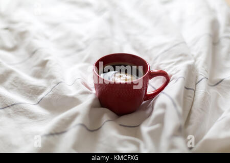 Kaffee in rot Schale serviert im Bett Stockfoto