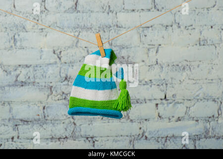 Baby Mütze und Turnschuhe trocken auf einem Seil auf einer weißen Wand. Stockfoto