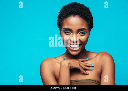 Nahaufnahme von Beauty Shot der Frau mit blauen Auge Schatten. Portrait von weiblichen Modell mit lebendigen Verfassung lachend auf blauem Hintergrund. Stockfoto