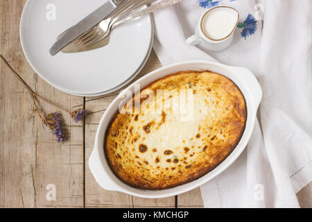 Quark Auflauf mit Rosinen, serviert mit Sahne, ein gesundes Frühstück im rustikalen Stil. Stockfoto