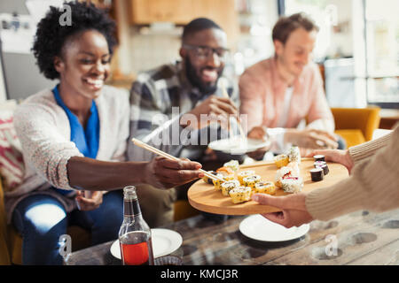 Freunde essen Sushi im Wohnzimmer Stockfoto