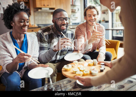 Freunde essen Sushi im Wohnzimmer Stockfoto