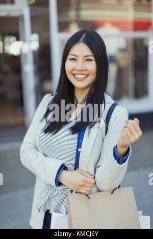 Portrait lächelnde junge Frau mit Einkaufstaschen Stockfoto
