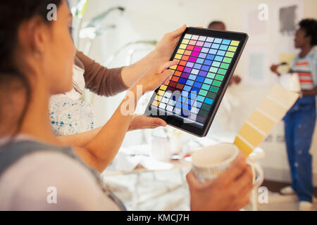 Junge Frau, die Kaffee trinkt und digitale Farbfelder anbetrachtet Digitales Tablet Stockfoto