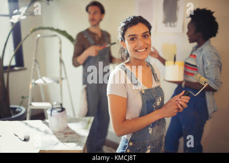 Portrait lächelnde junge Frau Malerei Wohnzimmer mit Freunden Stockfoto