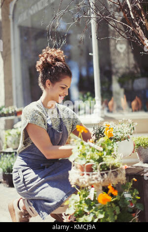 Weibliche Floristin Anordnung Display an sonnigen Blumengeschäft Schaufenster Stockfoto