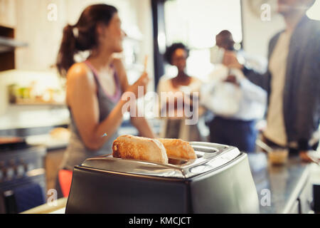 Freunde Mitbewohner reden hinter Toast im Toaster in der Küche Stockfoto