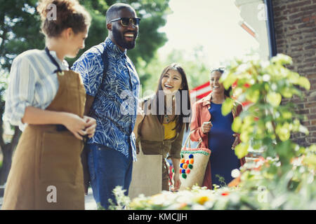 Weibliche Floristin hilft Freunden an sonnigen Blumengeschäft Schaufenster Stockfoto