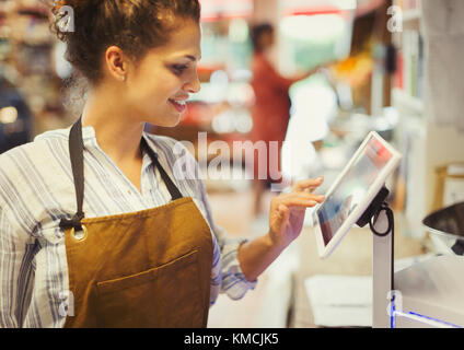 Weibliche Kassiererin mit Touchscreen-Kasse im Lebensmittelgeschäft Stockfoto