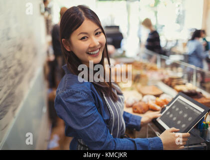 Portrait lächelnde, selbstbewusste Kassiererin an der Kasse im Café Stockfoto