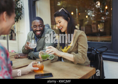 Lächelnde junge Freunde trinken Saft im Straßencafé Stockfoto