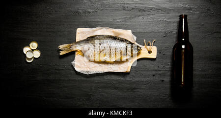 Das bier Konzept. Getrockneter Fisch und Bier Flasche auf dem Schwarzen Brett. top View Stockfoto