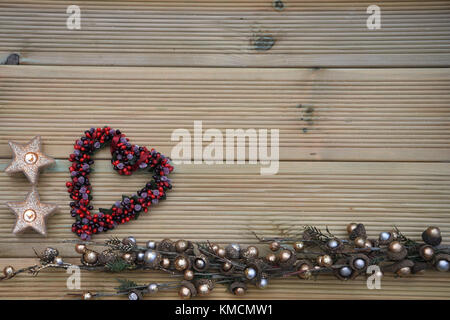 Romantische Weihnachtszeit fotografie Bild mit Deko Obst Beeren in Liebe Herz Form mit Kerzenlicht und rustikalem Holz Kopie Raum Hintergrund Stockfoto
