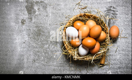 Eier in den Korb und Heu. Auf einem Stein Hintergrund. freier Platz für Text. top View Stockfoto