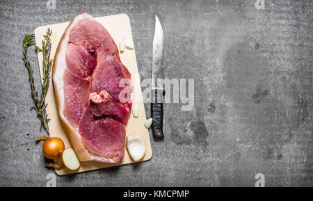 Ein Stück rohes Schweinefleisch mit Gewürzen und einem Messer. Auf den steinernen Tisch. freier Platz für Text. top View Stockfoto