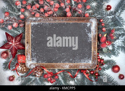 Tafel mit Platz für Ihren Grußtext mit Weihnachtsschmuck auf Schnee. Ansicht von oben, getönten Bild. Stockfoto