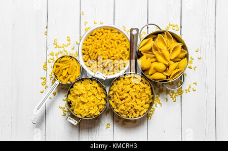 Viele verschiedene Arten von trockenen Nudeln in den Topf. Auf weissem Holztisch. top View Stockfoto