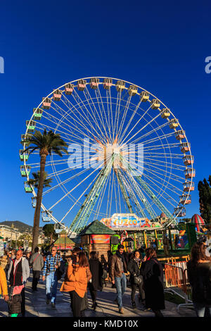 Place Masséna, Nizza, Frankreich, 5. Dezember 2017. Die Menschen genießen ein wunderschön sonnigen Tag mit blauem Himmel am schönen Weihnachtsmarkt. Die entspannte Atmosphäre des Marktes, mit Nahrung und Geschenk geht, Karussells, bunte Lichter und ein Riesenrad schön nimmt den Geist der Cote d'Azur festliche Jahreszeit. Stockfoto