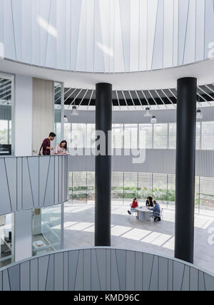 Geschäftsreisende treffen sich auf einem architektonischen, modernen Atrium-Balkon Stockfoto
