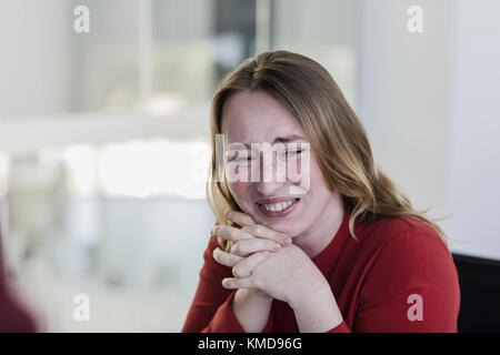 Geschäftsfrau lachend mit Händen zusammengeklemmt Stockfoto