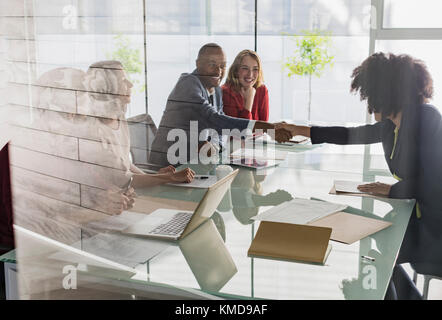 Geschäftsmann und Geschäftsfrau Handshaking über Konferenztisch in der Sitzung Stockfoto