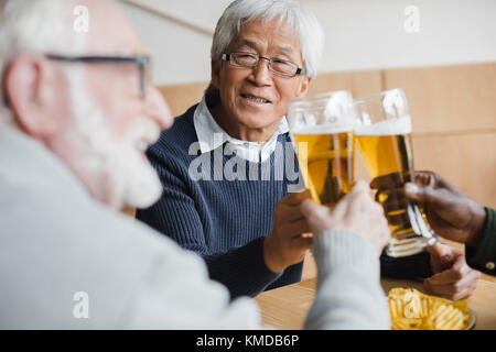 Ältere Freunde klirren Gläser Bier Stockfoto