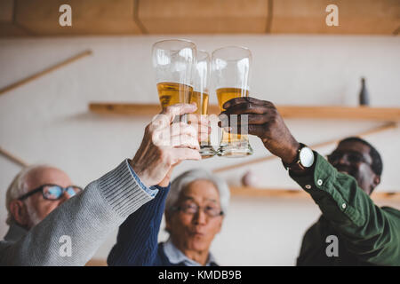 Ältere Freunde klirren Gläser Bier Stockfoto