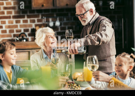 Ältere Menschen gießen Wein für Frau Stockfoto