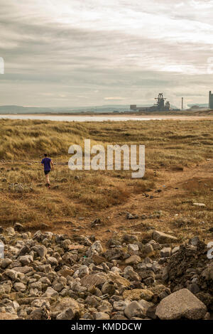 Ein Mann mittleren Alters jogg am Ufer entlang bei Paddys Hole, Redcar, England, Großbritannien Stockfoto