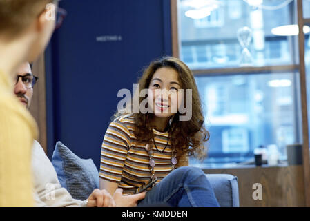 Asiatische Geschäftsfrau in einer Diskussion mit kaukasischen Kollegen in einem modernen Büro Stockfoto