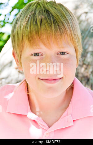 Lächelnde Junge in rosa Hemd in der Nähe von Tree Stockfoto