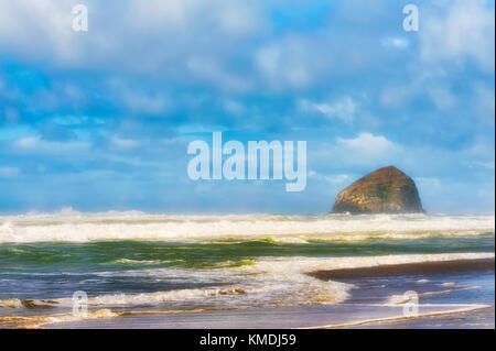 Wellen in bei bewölktem Himmel auf einsamen Strand mit Haystack Rock im Hintergrund bei Pacific Stadt an der Küste von Oregon Stockfoto