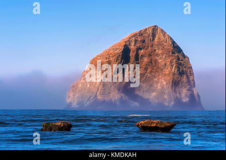 Nebel rollt enthüllt Haystack Rock am Cape Kiwanda in Pacific City, Oregon Stockfoto