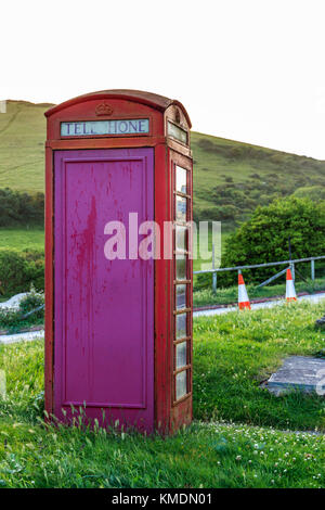 Eine verwitterte, traditionelle britische K6-Telefondose, entworfen von Sir Giles Gilbert Scott, in Lulworth Cove, Dorset, England, Großbritannien Stockfoto