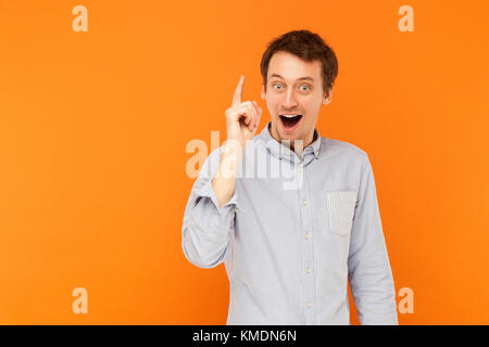 Tolle Idee! Junge erwachsene Mann Finger nach oben, haben sie eine kreative Idee. Studio shot, orange Hintergrund Stockfoto